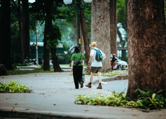 Couple walking together along a tree-lined park path on a sunny day